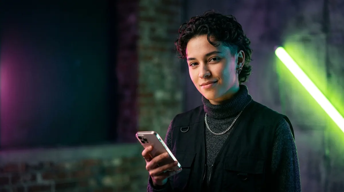 A creator lit in neon, holding their phone